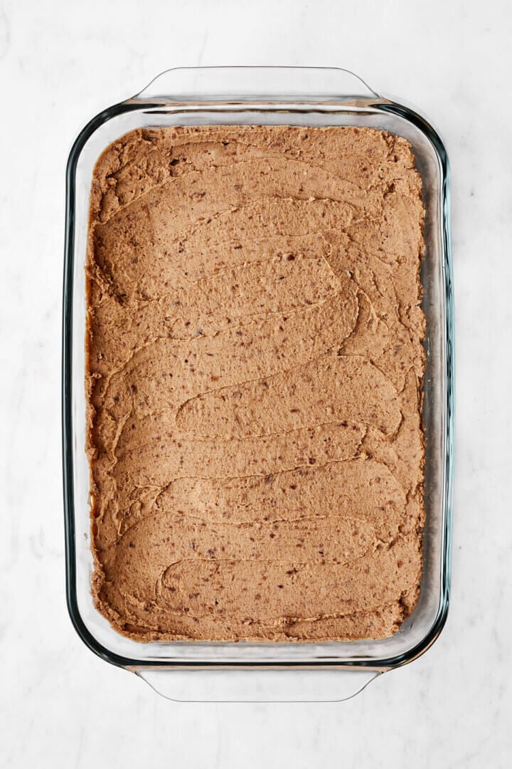 A layer of refried beans in a casserole dish for 7 layer dip