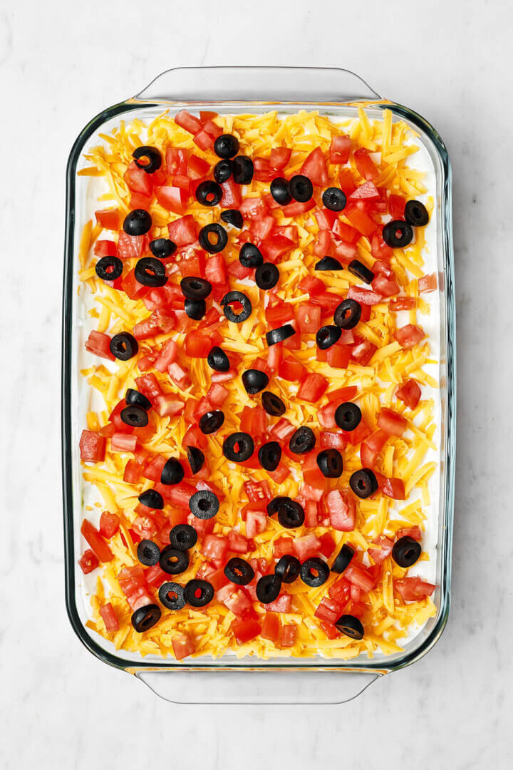 Adding tomatoes and olives for 7 layer dip