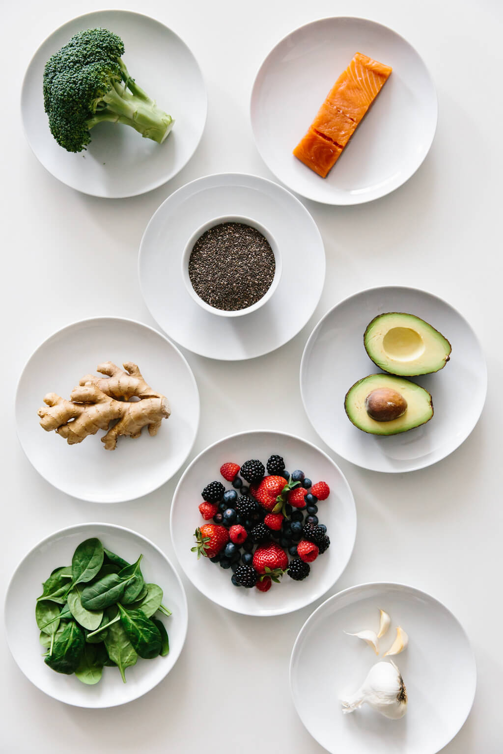 Eight plates of individual anti-inflammatory ingredients on white table. 