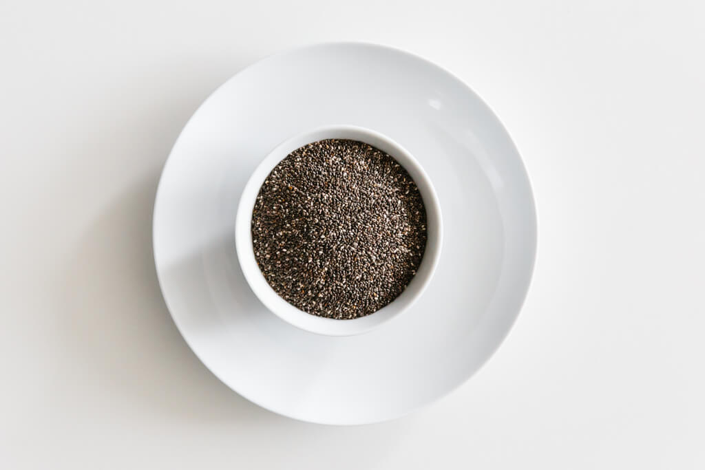 Bowl of chia seeds on a white table.