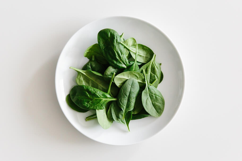 Plate of spinach on a white table.