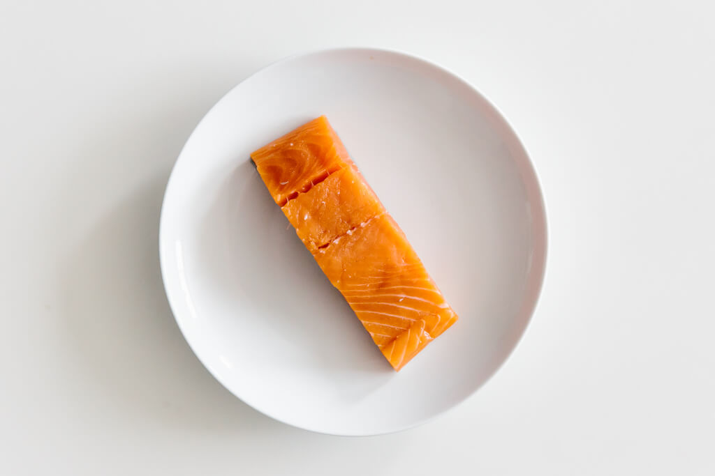 Plate of salmon on a white table.