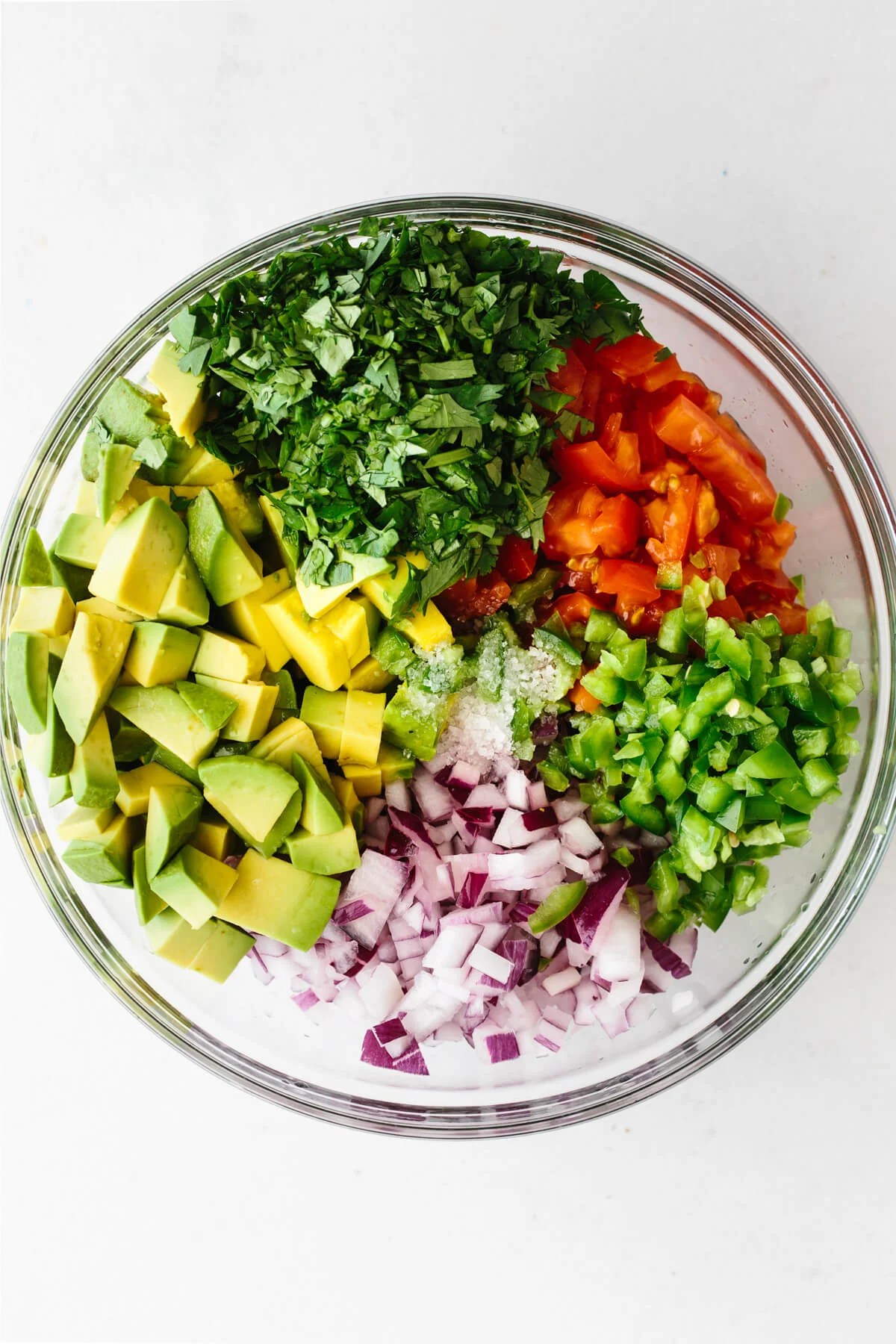 A mixing bowl with the ingredients to make avocado salsa.