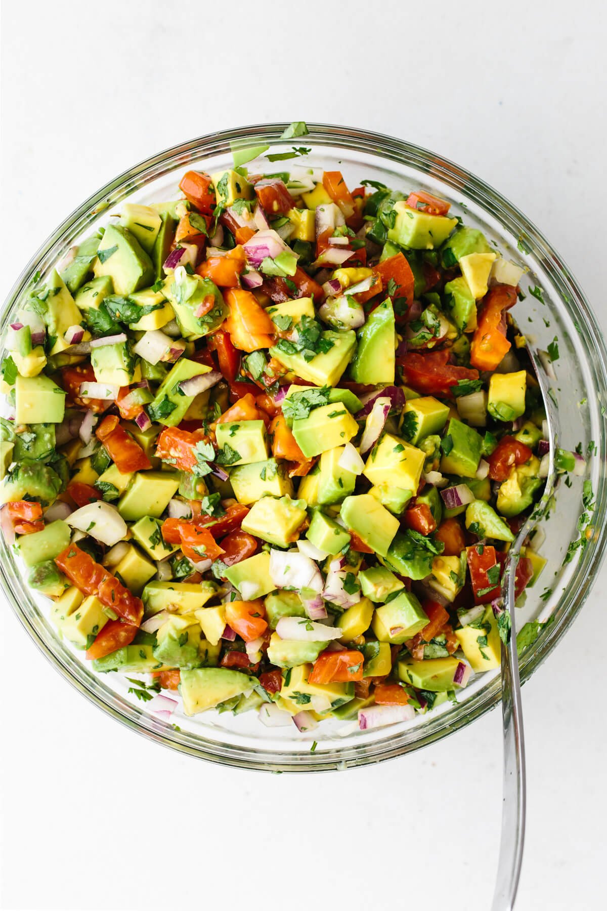 The avocado salsa ingredients stirred and mixed together in a bowl.