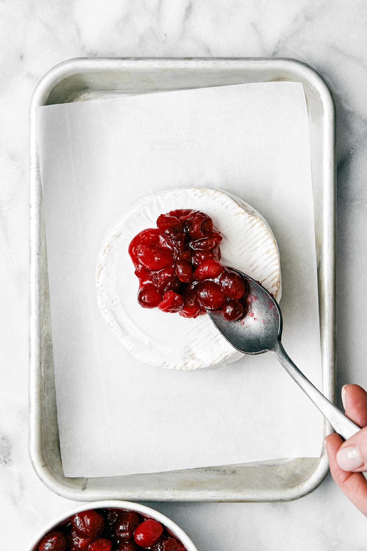 Adding a spoonful of cranberry sauce on brie.