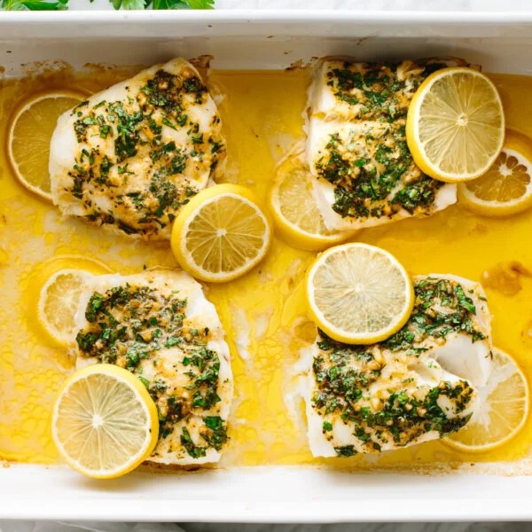 Baked cod in a baking dish with lemon slices.