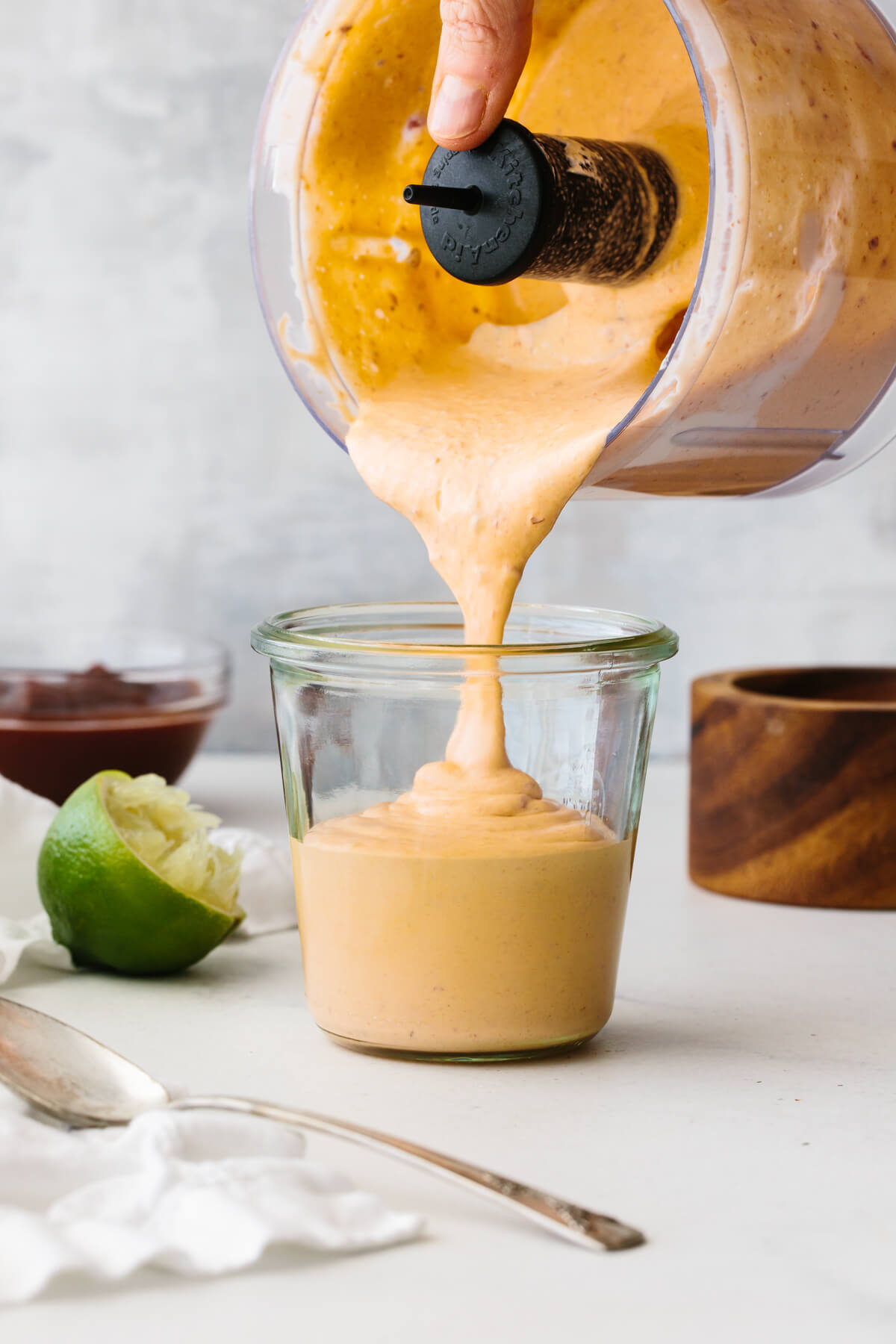 Pouring chipotle sauce from food processor into a glass jar.