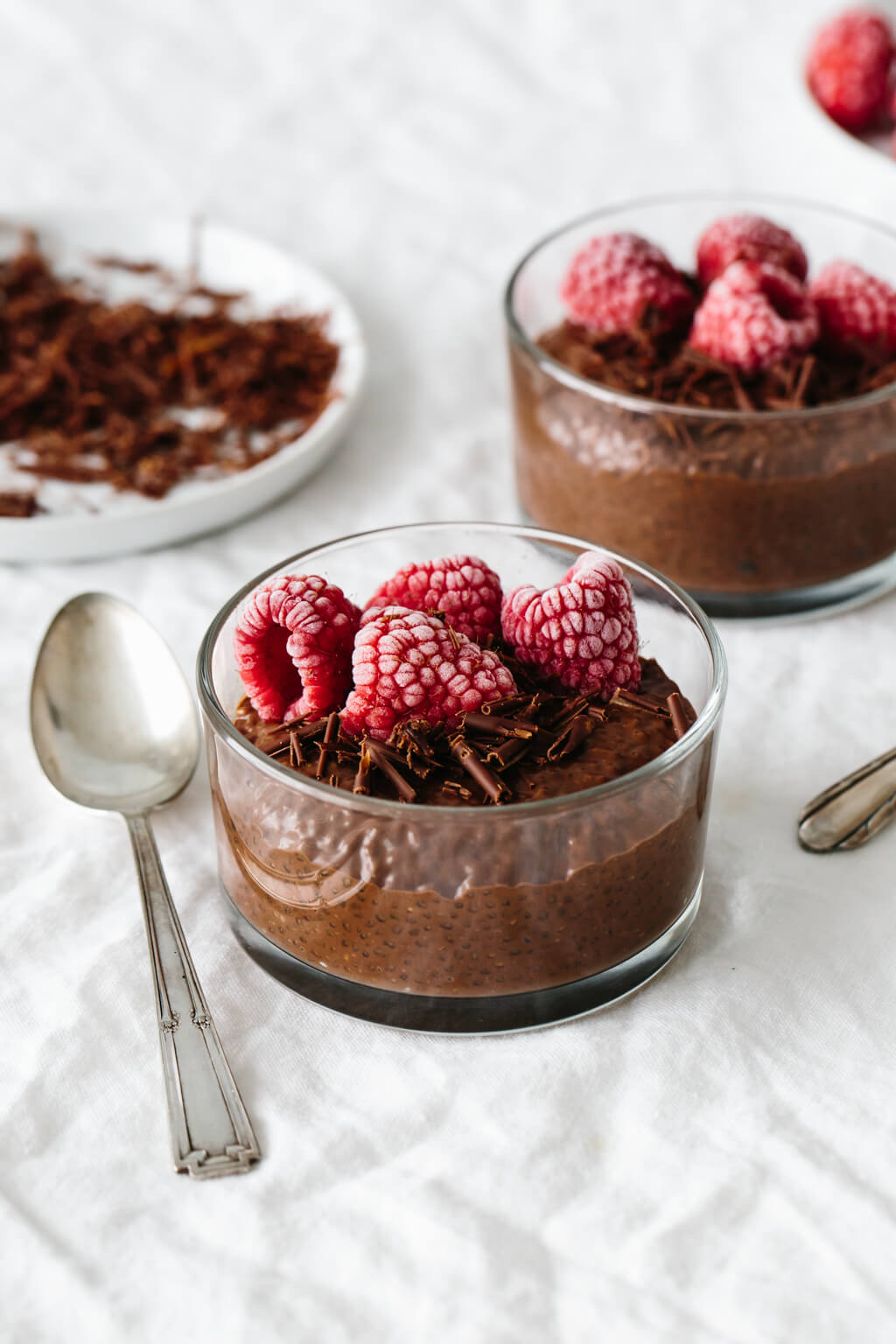 Chocolate chia pudding in a dessert glass with frozen, frosted raspberries on top.