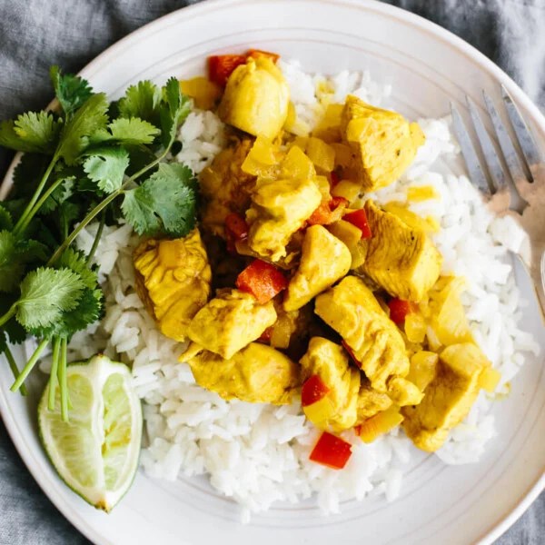 Coconut curry chicken on a bed of rice on a plate.