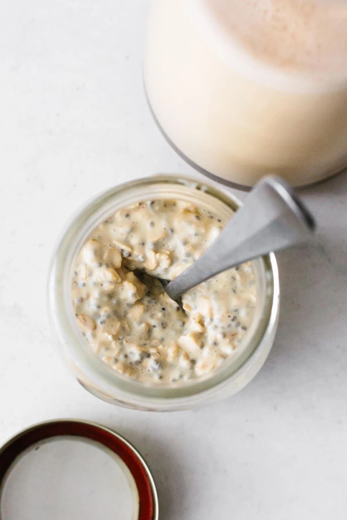 A jar of eggnog overnight oats with a spoon.