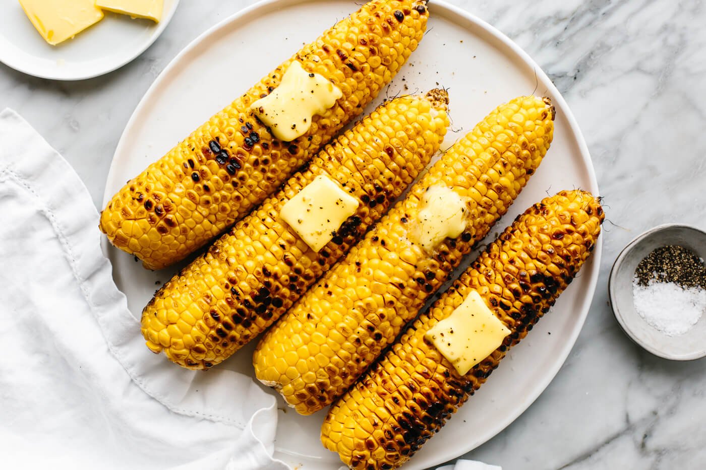 A plate of four grilled corn on the cobs