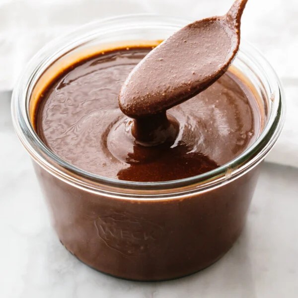 A spoon with a jar of homemade Nutella.