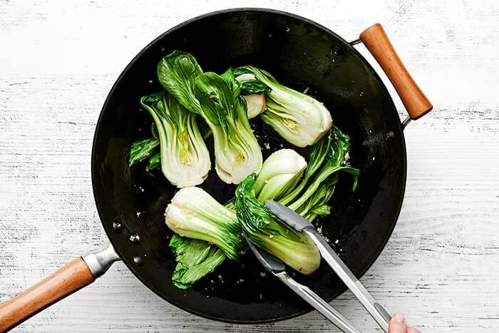 Cooked bok choy in a wok.