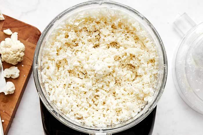 A food processor with grated cauliflower in it.