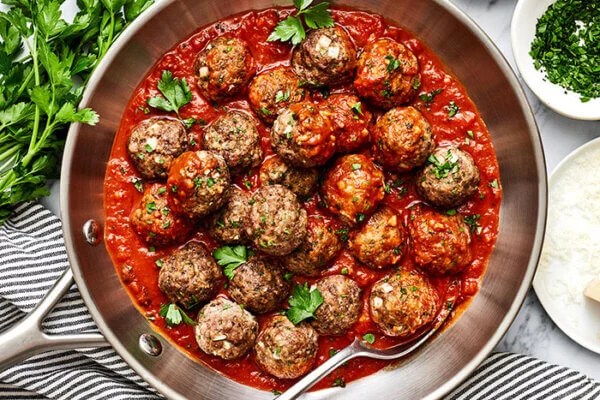 A pan of baked meatballs simmered in marinara sauce