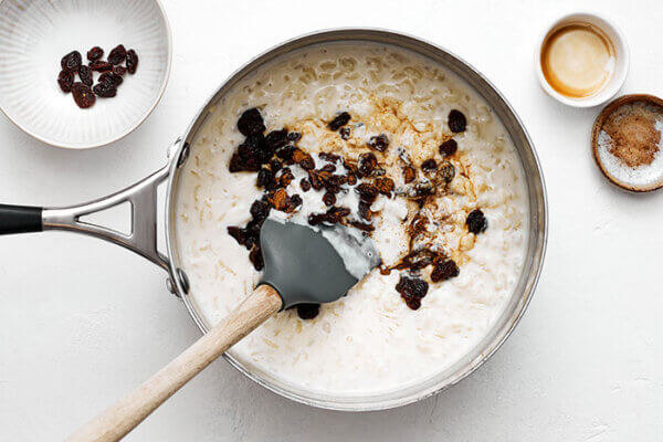 Stirring raisins and cinnamon into a pot of rice pudding