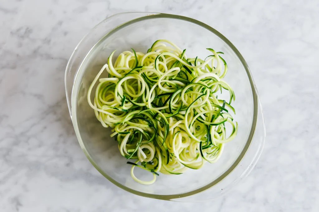 Zucchini noodles in a microwave safe glass bowl.