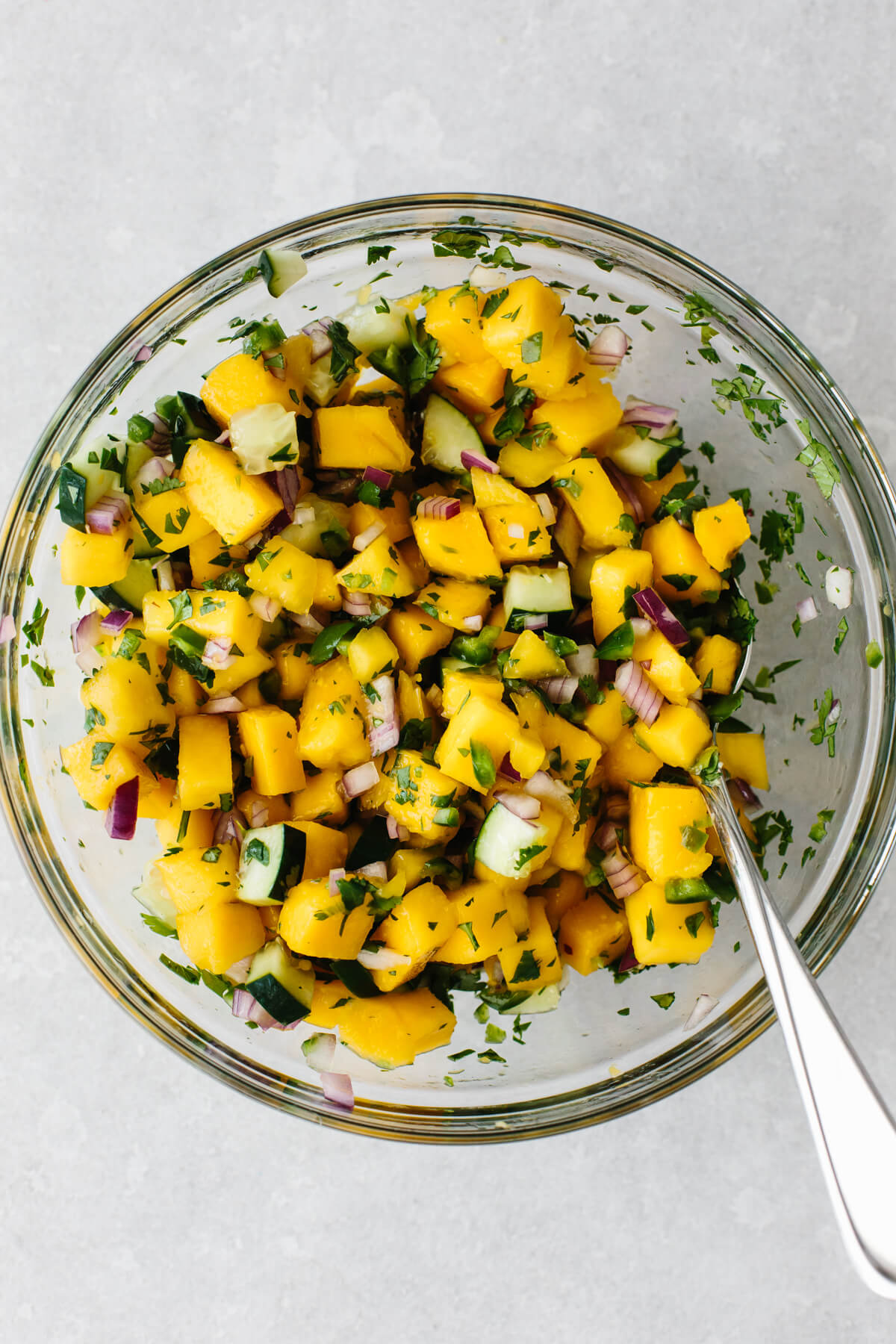 Mixing mango salsa in a bowl.