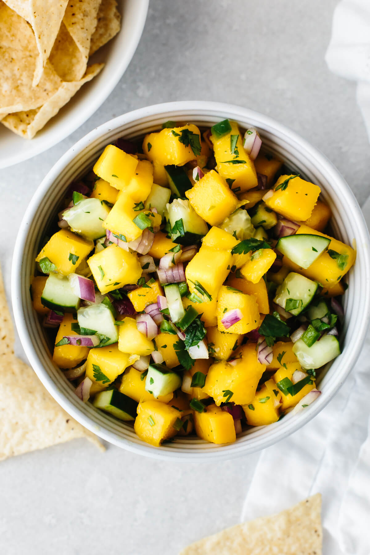 Mango salsa in a bowl next to chips.
