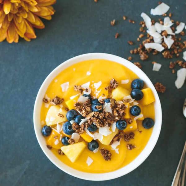 (gluten-free) Mango Smoothie Bowl. The perfect summer smoothie bowl, filled with mangoes, pineapple, blueberries and gluten-free granola.