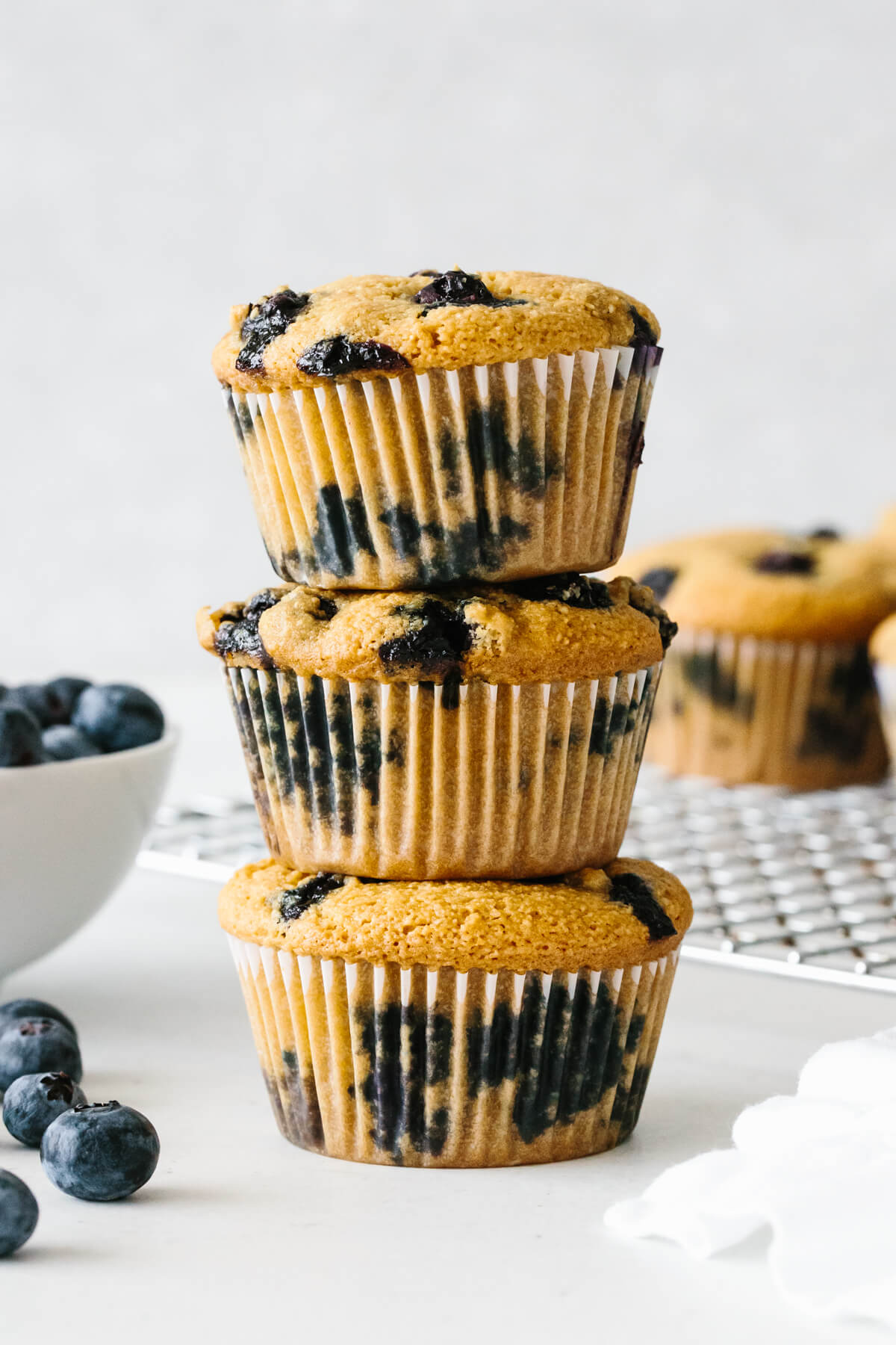 Three paleo blueberry muffins stacked on top of each other.