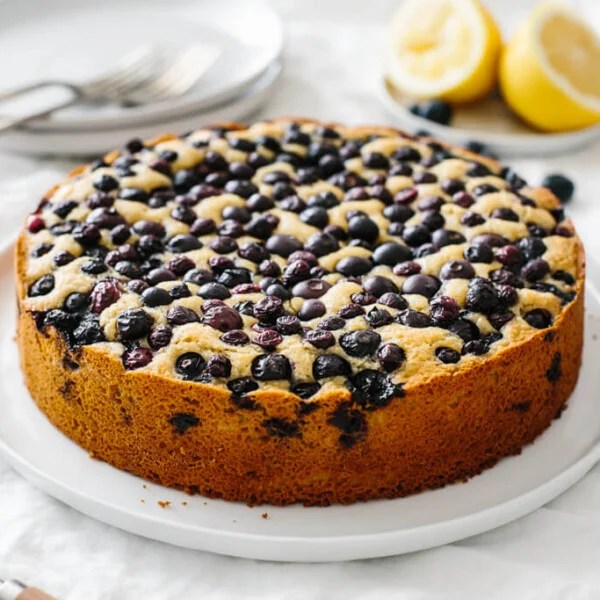 A lemon cake topped with blueberries on a table.