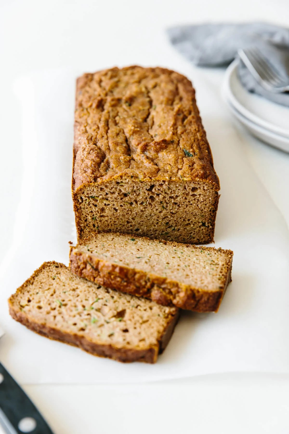 Paleo zucchini bread on a table with two slices from the loaf.