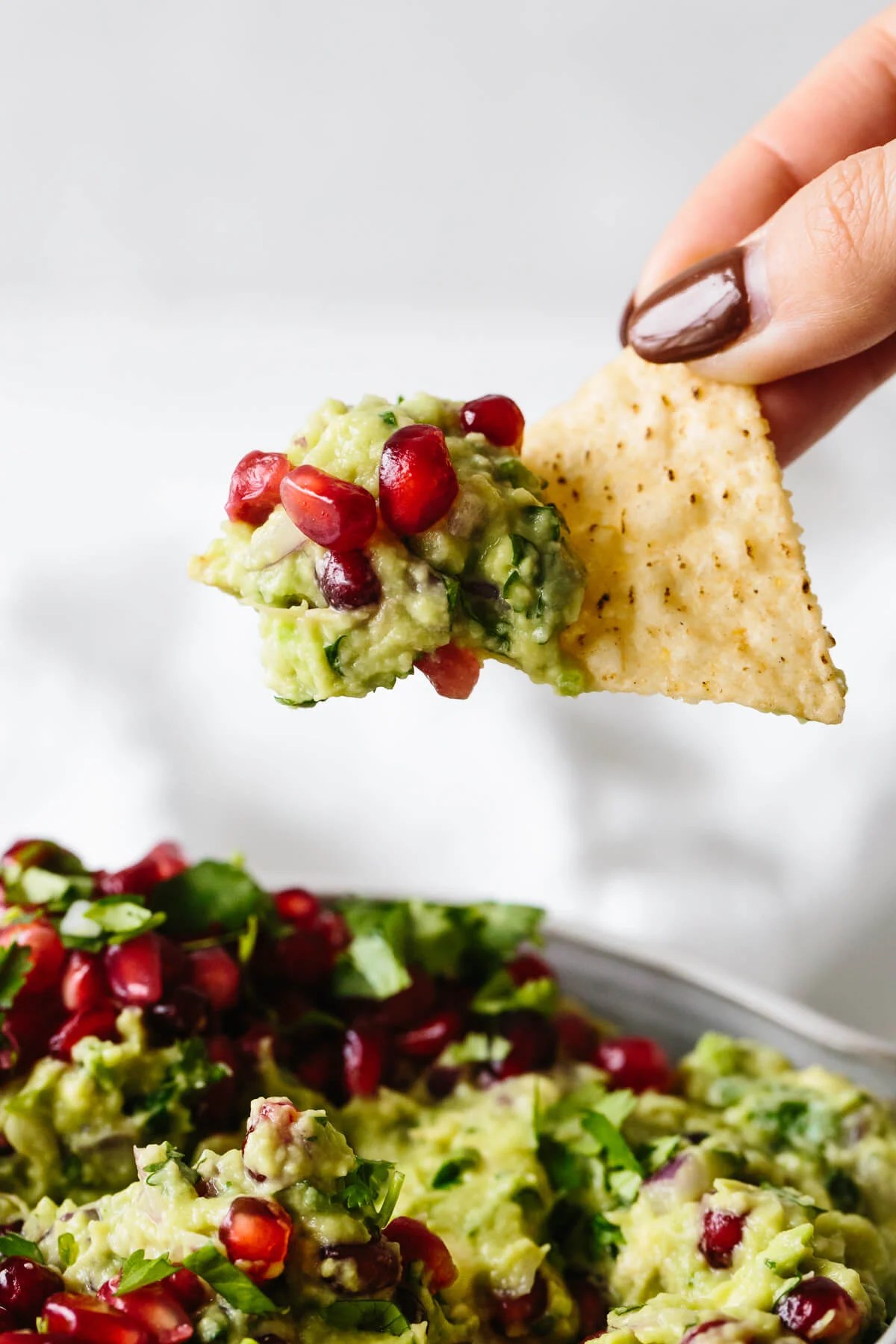 Scooping up pomegranate guacamole with a tortilla chip.