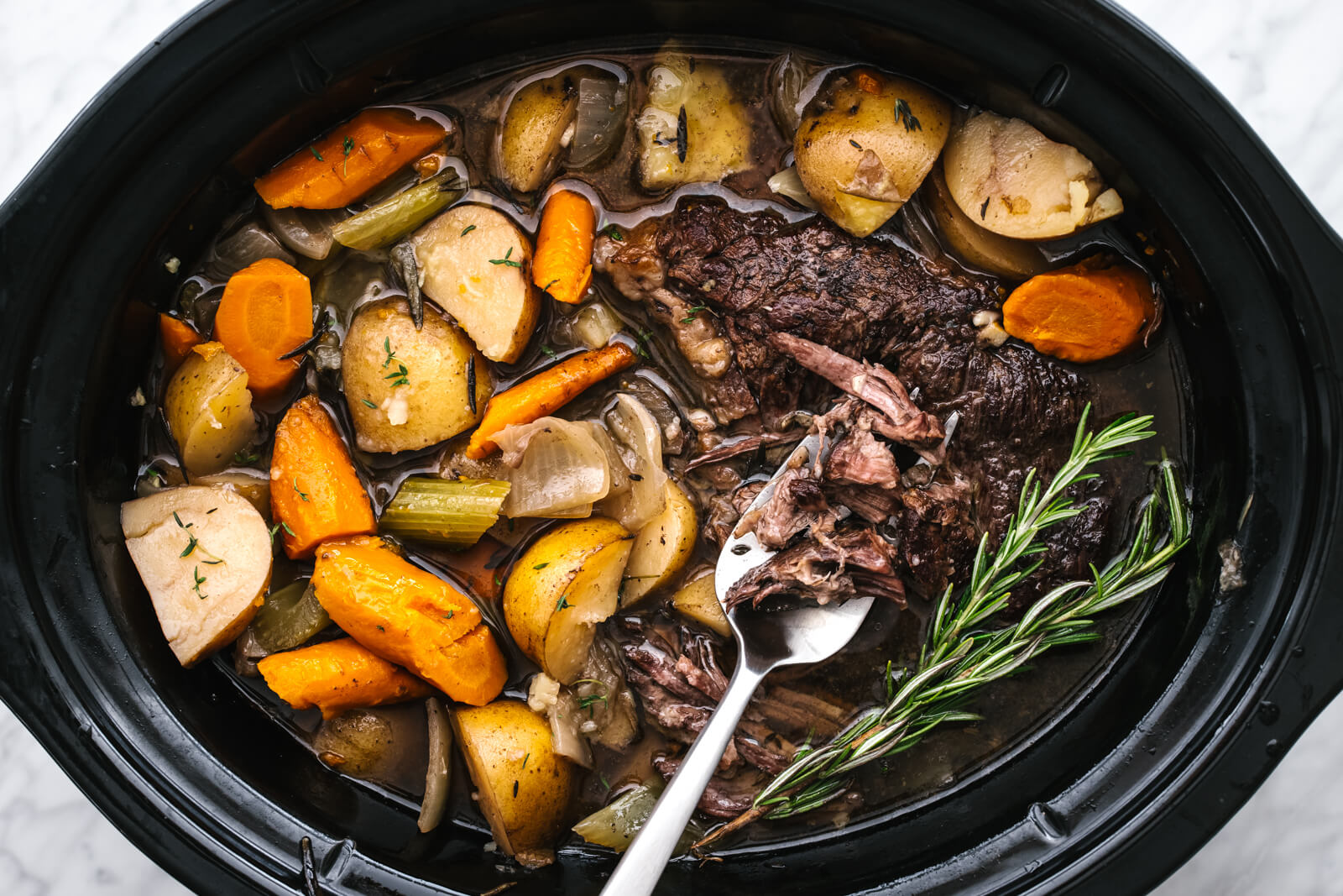A slow cooker with pot roast in it