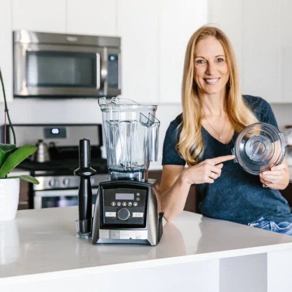 Girl standing next to Vitamix Blender pointing to the lid.